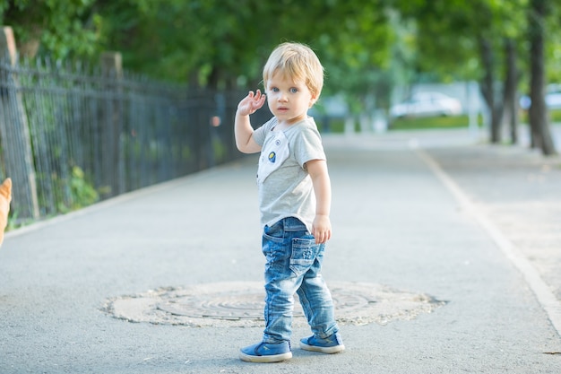 屋外の公園を歩いている幸せな笑顔の幼児の男の子