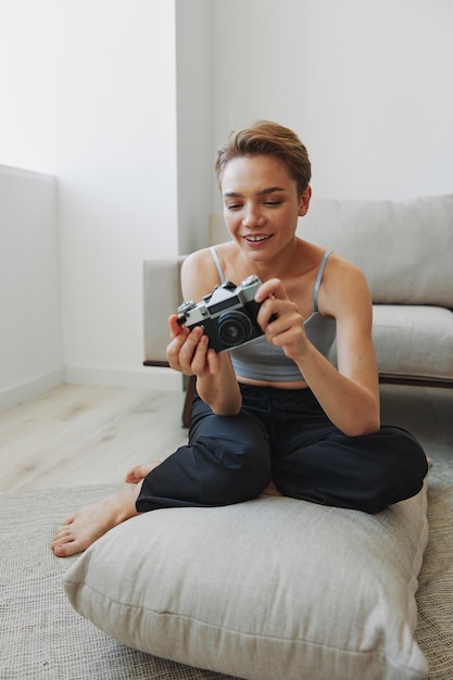 Happy smile woman holding an old camera and taking pictures of herself as a weekend photographer in home clothes with a short haircut hair without filters on a white background free copy space