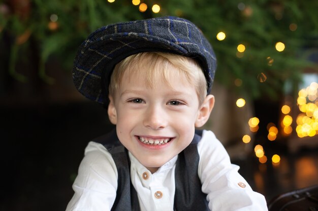 Happy smiley little boy near Christmas tree