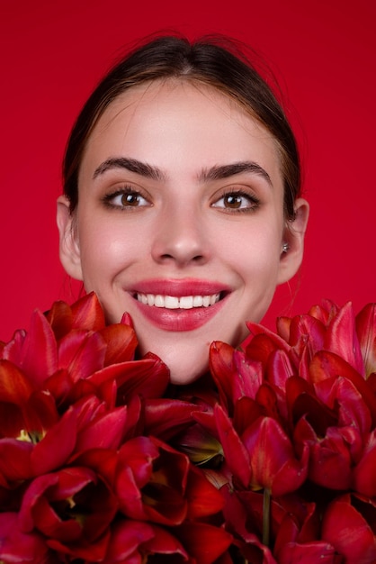 チューリップの花を持つ幸せな笑顔の女性美しい官能的な女性はチューリップの花束を保持します