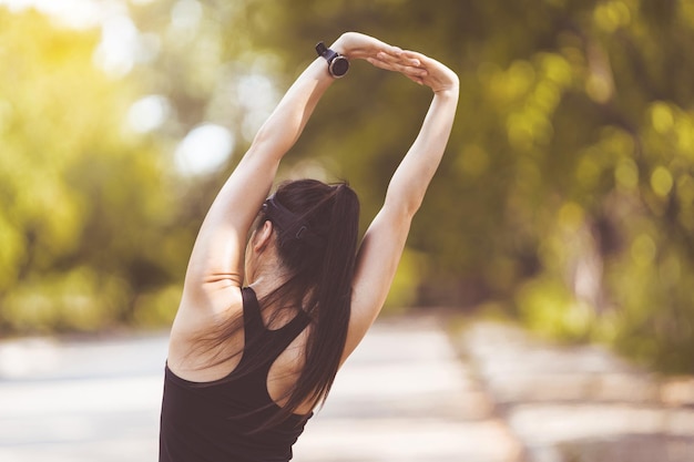 Happy smiling adult Asian woman jogging outdoor in the city park in sunshine beautiful summer day.  Happy relaxed mature woman jogging to live an active and healthy lifestyle