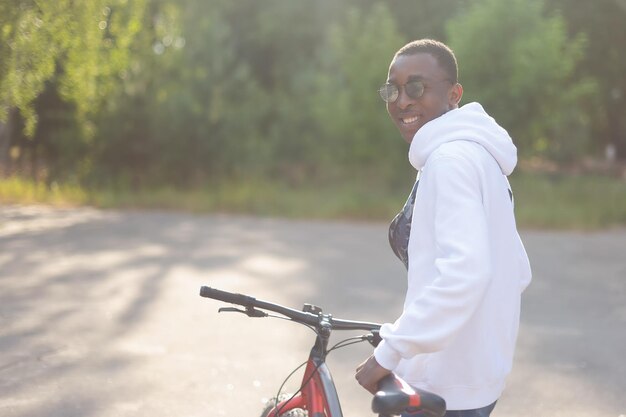 A happy smiling African American man walks down the street with a bicycle Sports and recreation