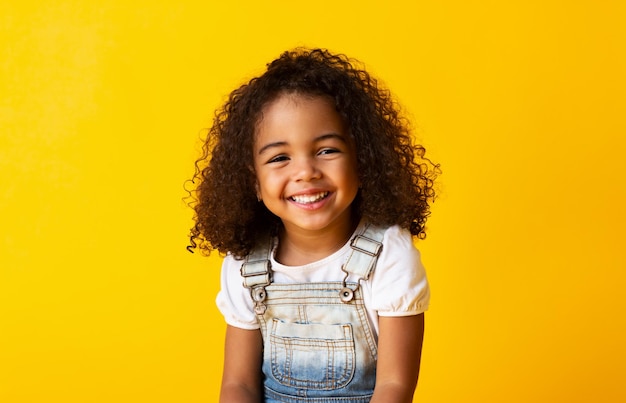 Photo happy smiling africanamerican child girl yellow background
