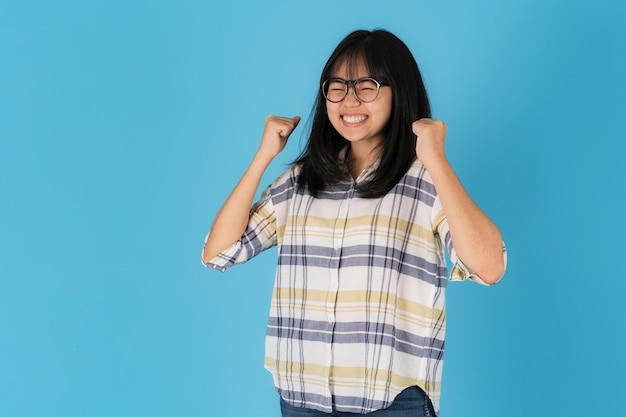 Счастливая улыбающаяся азиатская девушка, стоящая на синем фоне