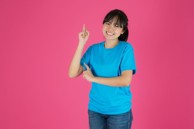 Happy smiling asian girl standing on pink background