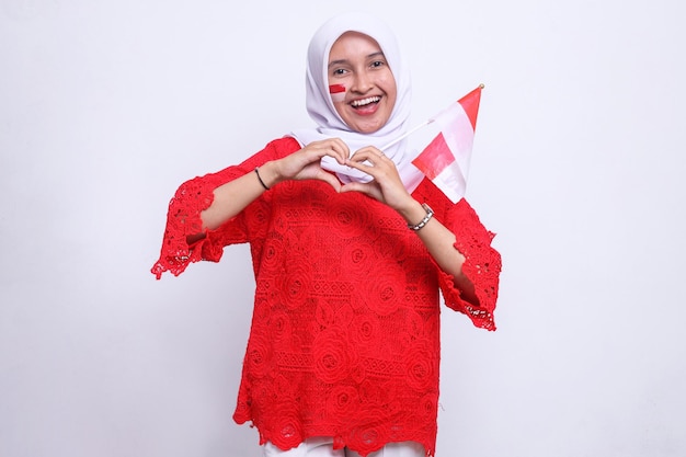 Happy smiling asian indonesian woman holding indonesia flag and showing love sign