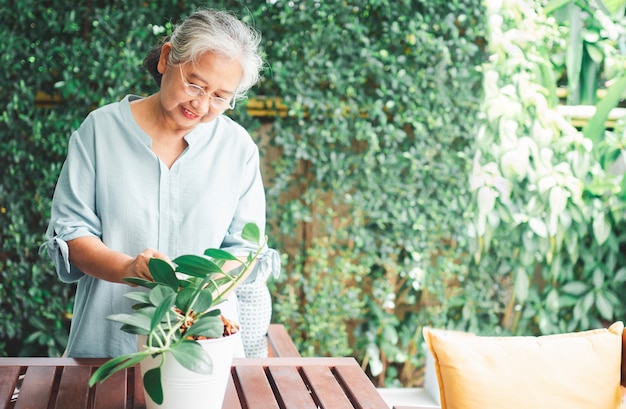 幸せで笑顔のアジアの老婆が引退後の趣味のために植えています