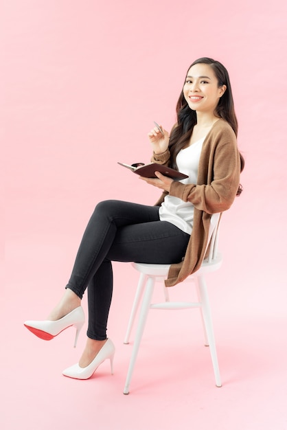 Happy smiling asian woman with diary sitting in chair