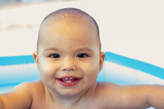 Happy smiling baby boy in an inflatable pool