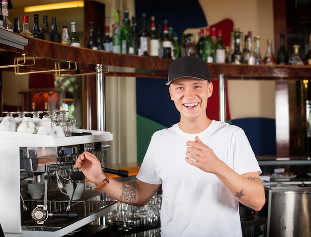 Happy smiling barista or bartender next to the coffee machine.