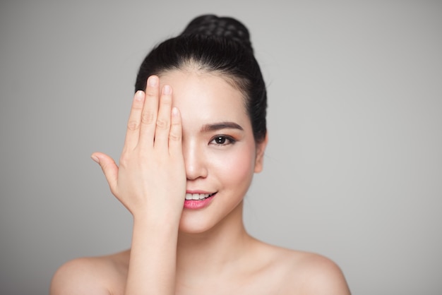 Happy smiling beautiful asian woman touching her face.