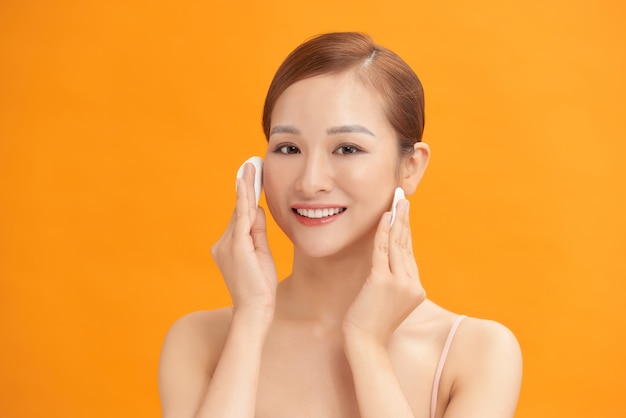 Happy smiling beautiful asian woman using cotton pad cleaning skin