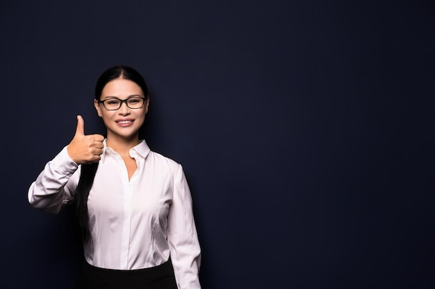 Happy smiling beautiful young business woman showing okay gesture, isolated over dark wall