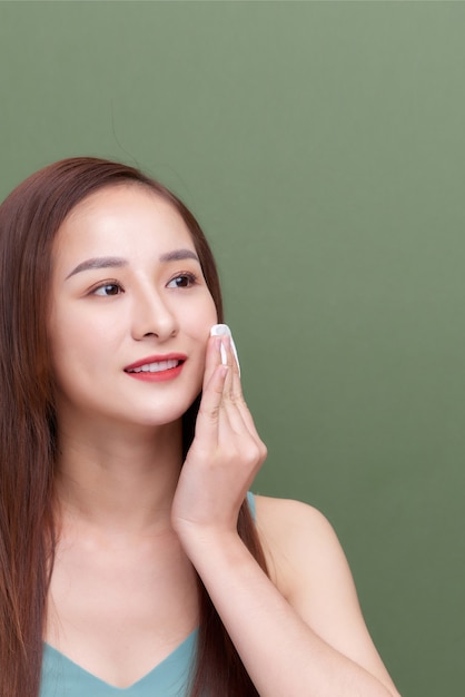 Happy smiling beautiful young woman cleaning skin by cotton pad.