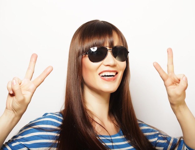 Happy smiling beautiful young woman showing two fingers or victory gesture over white background