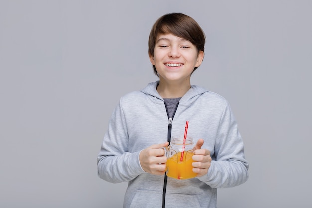 Happy smiling boy drinking fresh juice from glass with a straw