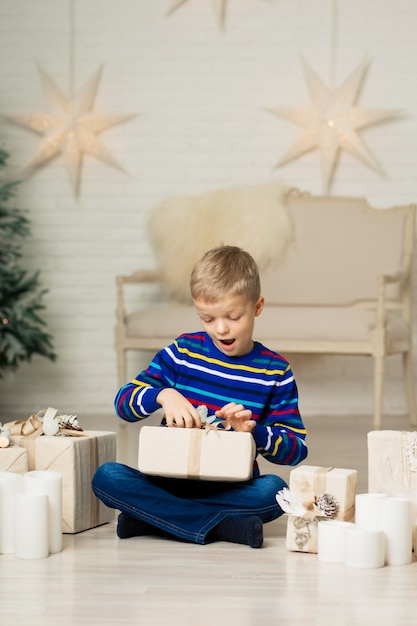 幸せな笑顔の少年はクリスマスギフトボックスを保持します