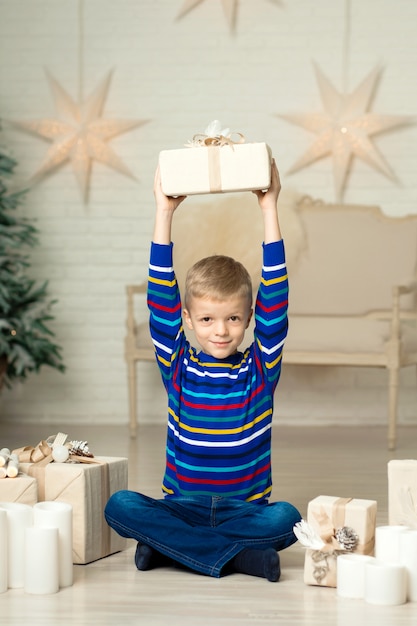 幸せな笑顔の少年はクリスマスギフトボックスを保持します