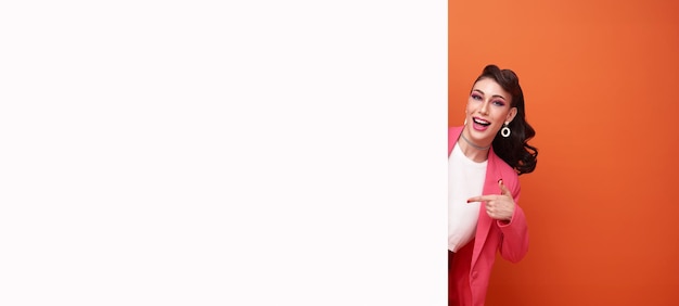 happy smiling business woman in pink blazer hand pointing finger blank announcement banner