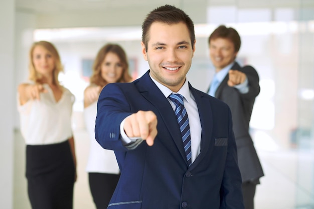 Happy smiling businessman and his colleagues pointing by finger into the camera Concept of employer and success team