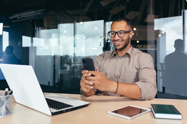 Happy and smiling businessman rejoicing at successful work\
results and achievement man at work using