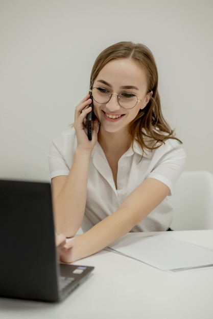 Donna di affari sorridente felice che ha una chiamata di lavoro, discutere di riunioni, pianificare la sua giornata di lavoro, utilizzando lo smartphone