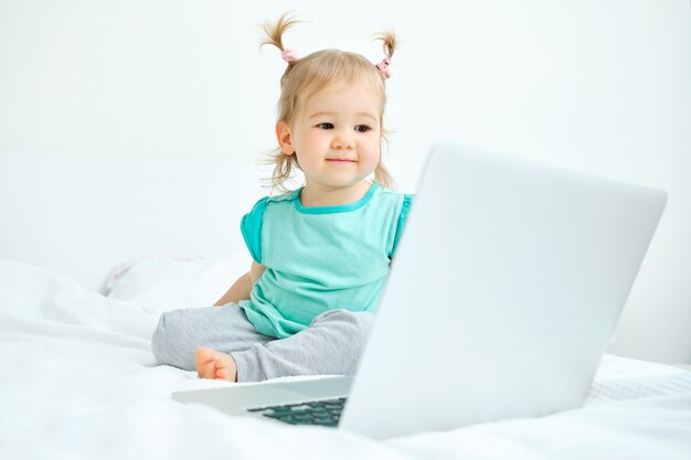 Happy smiling caucasian kid girl looking at laptop