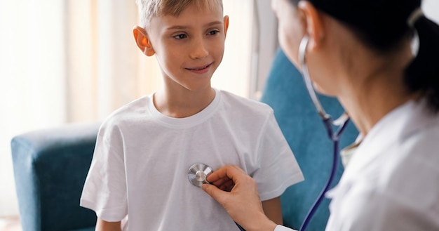 Happy smiling child patient at usual medical inspection. Doctor and kid boy at home. Medicine, healthcare concepts.