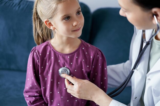 Happy smiling child patient at usual medical inspection Doctor and kid patient at home Medicine healthcare concepts