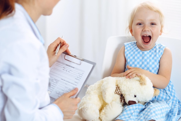 Happy smiling child patient at usual medical inspection. Doctor and patient in clinic. Medicine, healthcare concepts.