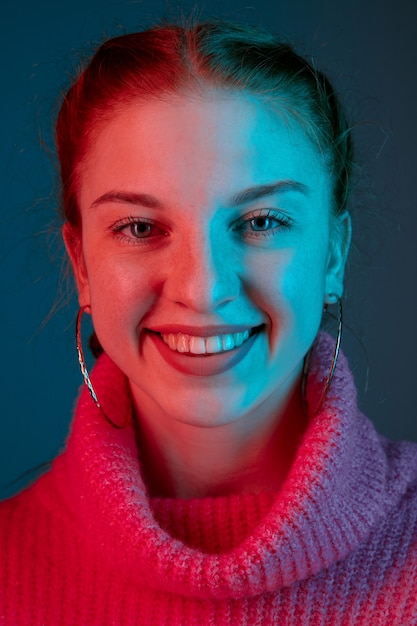 Happy smiling, close up. Caucasian woman's portrait isolated on gradient studio background in neon light. Beautiful female model with red hair. Concept of human emotions, facial expression, sales, ad.