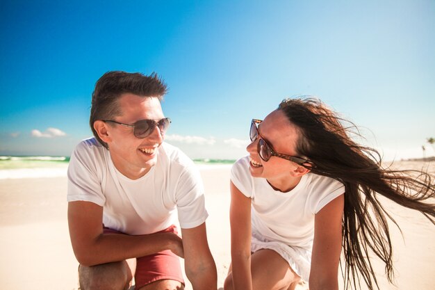 Coppie sorridenti felici sulla spiaggia bianca esotica che esamina macchina fotografica