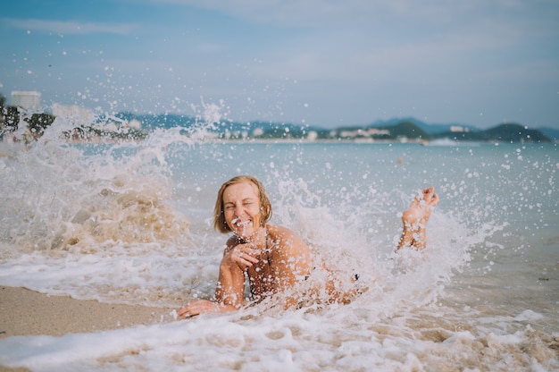 Turista senior anziano emozionante sorridente felice della donna che gioca in acqua e che nuota nelle grandi onde sulla spiaggia del mare dell'oceano. in viaggio lungo l'asia, concetto di stile di vita attivo.