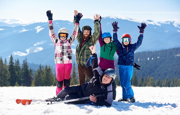 겨울 산 배경의 깊은 눈 속에서 스키와 스노우보드를 타고 행복한 미소 짓는 가족