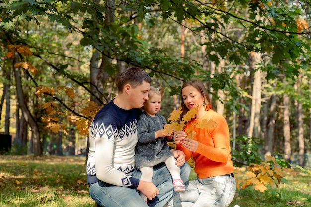 Счастливая улыбающаяся семья, расслабляющаяся в осеннем парке