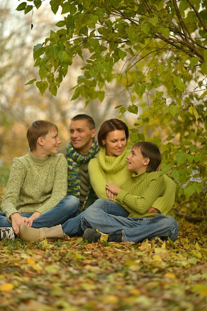 Фото Счастливая улыбающаяся семья, расслабляющаяся в осеннем парке