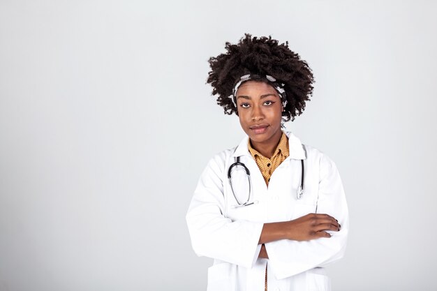 Medico femminile sorridente felice in camice bianco con lo stetoscopio sopra priorità bassa