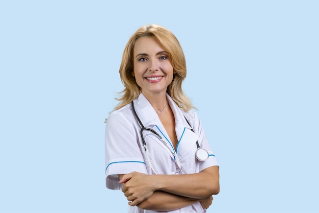 Счастливая улыбающаяся женщина-доктор со сложенными руками изолирована на синем