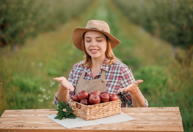 Happy smiling female farmer worker crop picking fresh ripe apples in orchard garden during autumn harvest Harvesting time