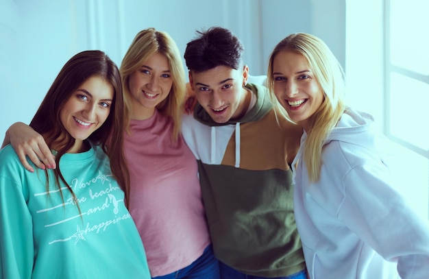 Happy smiling friends group of young people standing and embracing together