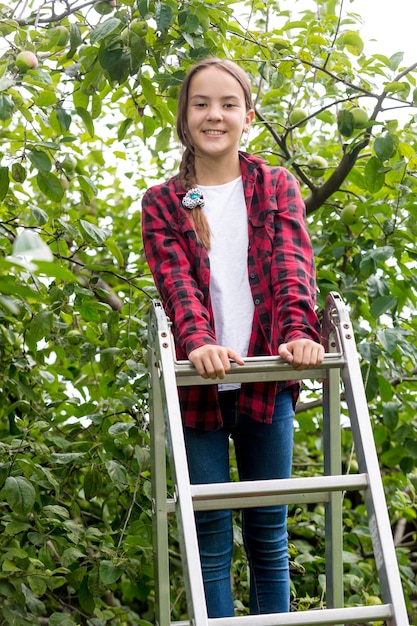 Ragazza sorridente felice che sale la scala a libro in giardino