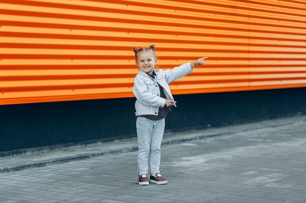 Ragazza sorridente felice in jeans che indica con le sue dita