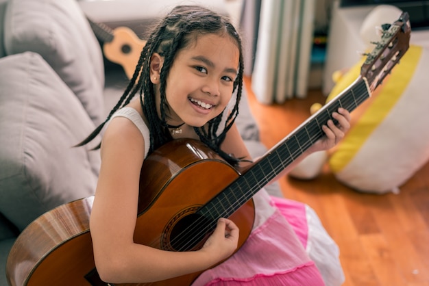 Happy smiling girl ,learning to play the acoustic guitar