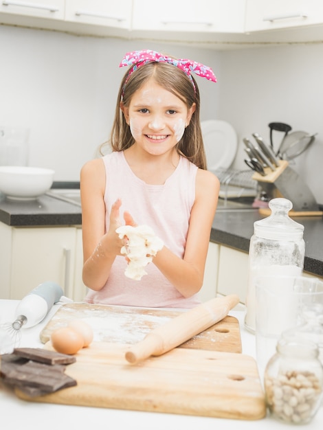 Ragazza sorridente felice che fa l'impasto per la torta in cucina