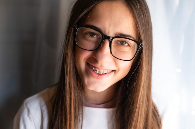 Happy smiling girl with dental braces and glasses. Funny expression. Adolescence.