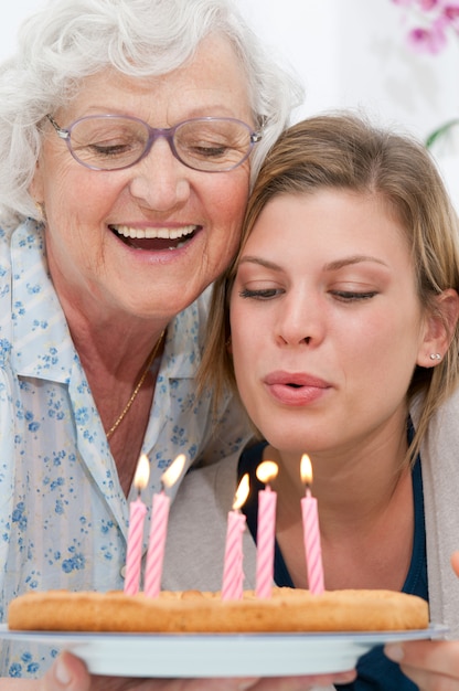 幸せな笑顔の祖母を祝って、自宅で彼女の孫に誕生日ケーキを与える