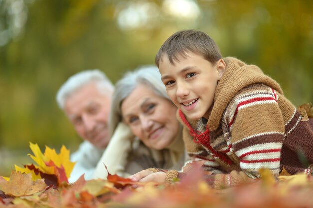 Happy smiling grandparents with their grandson in autumn forest