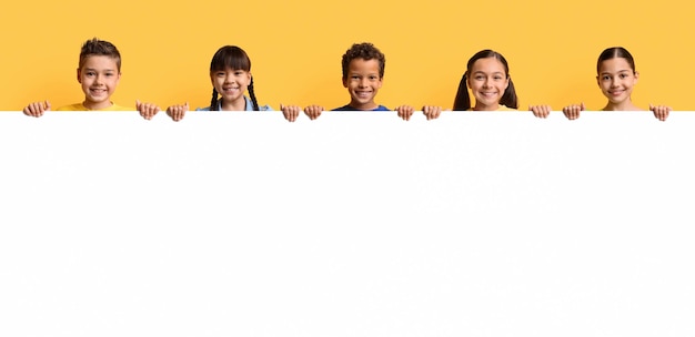 Photo happy smiling group of kids showing blank placard board