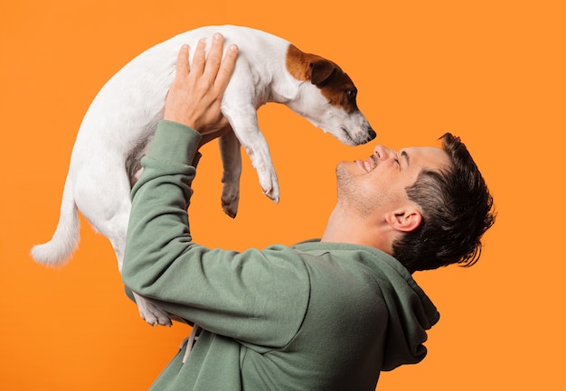 Photo happy smiling guy with a dog on orange