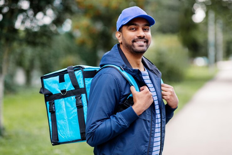 Photo happy smiling indian delivery man with bag in city